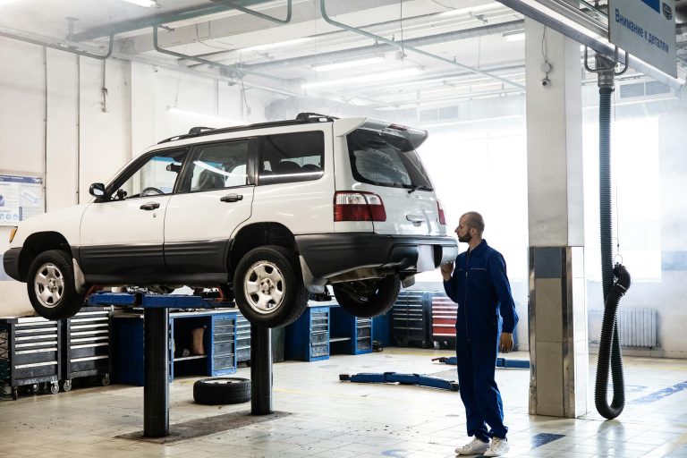 Mechanic inspecting a lifted SUV in a modern auto repair garage.